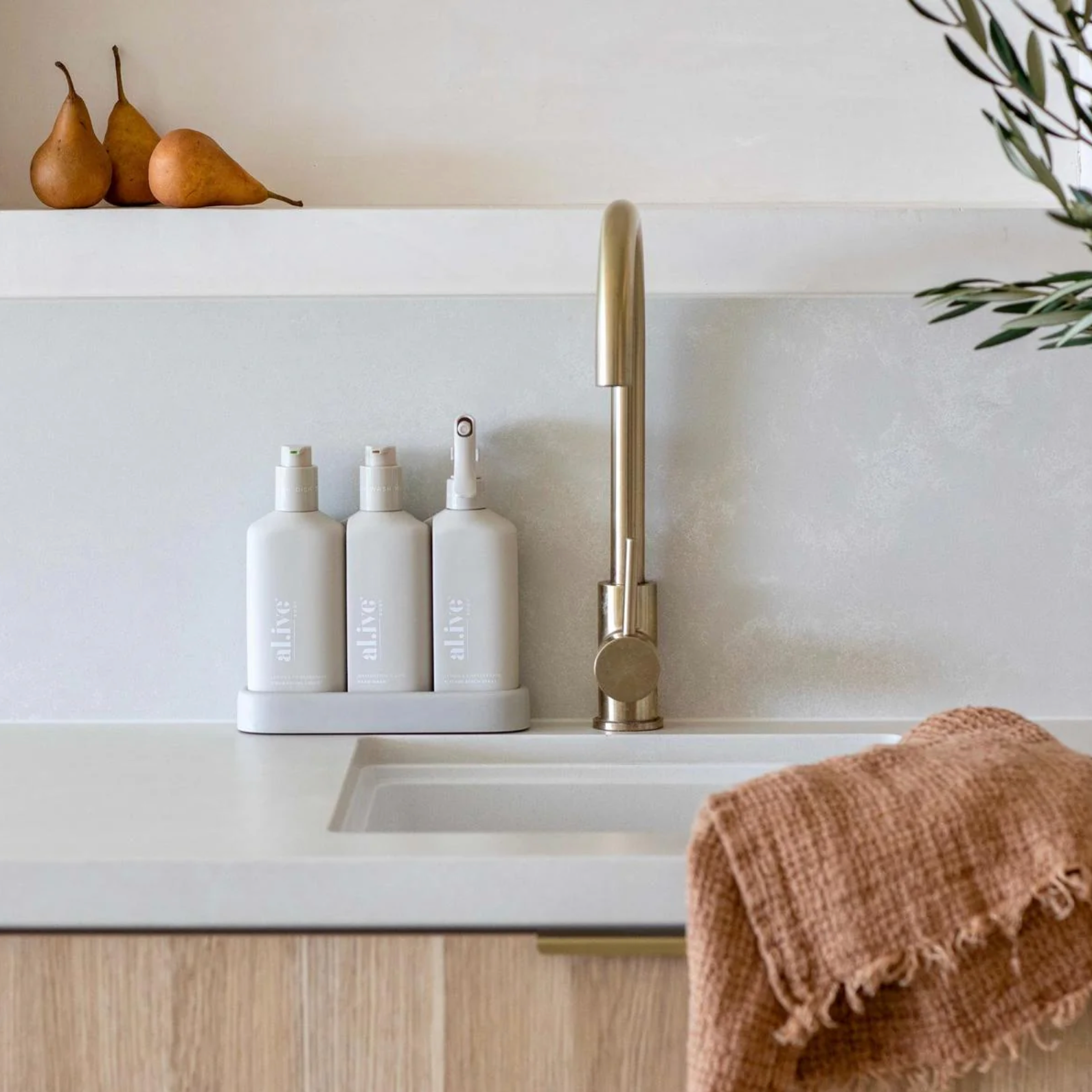 Modern kitchen sink with white countertop, gold faucet, and decorative elements.