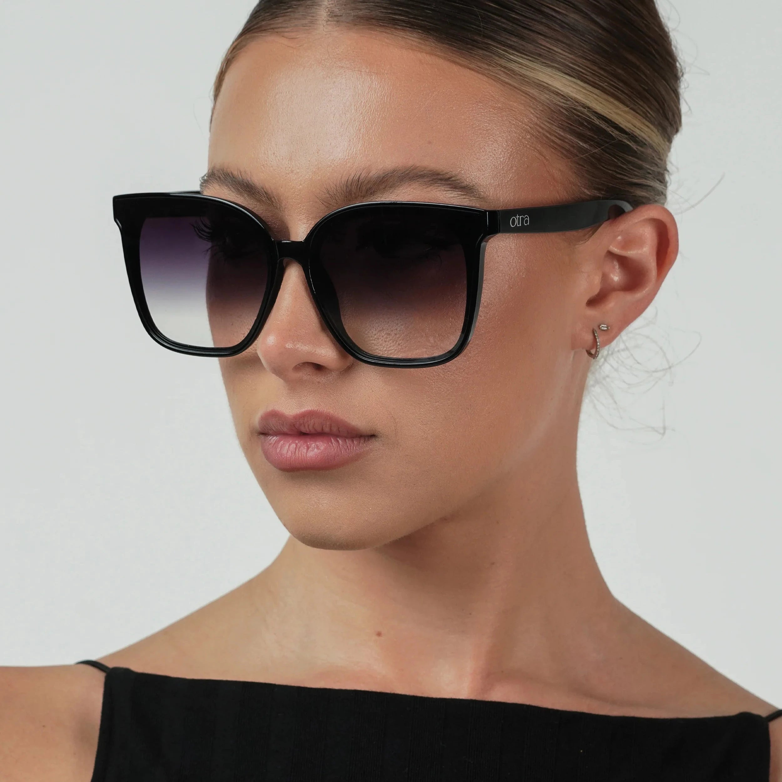 Woman wearing black cat-eye sunglasses against a plain background