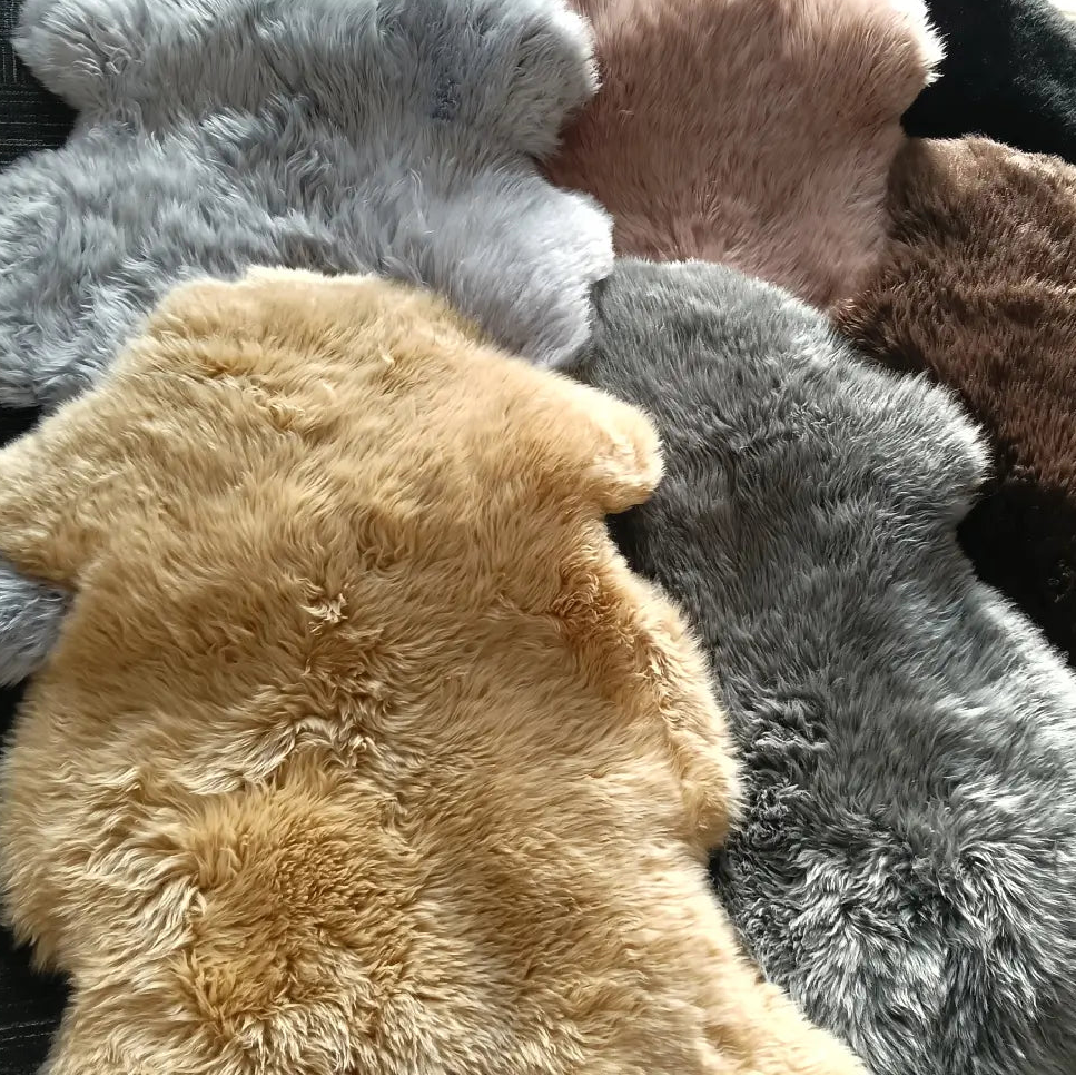 A group of fluffy sheepskin rug pieces in multiple colours, including stone, taupe, dark brown, honey