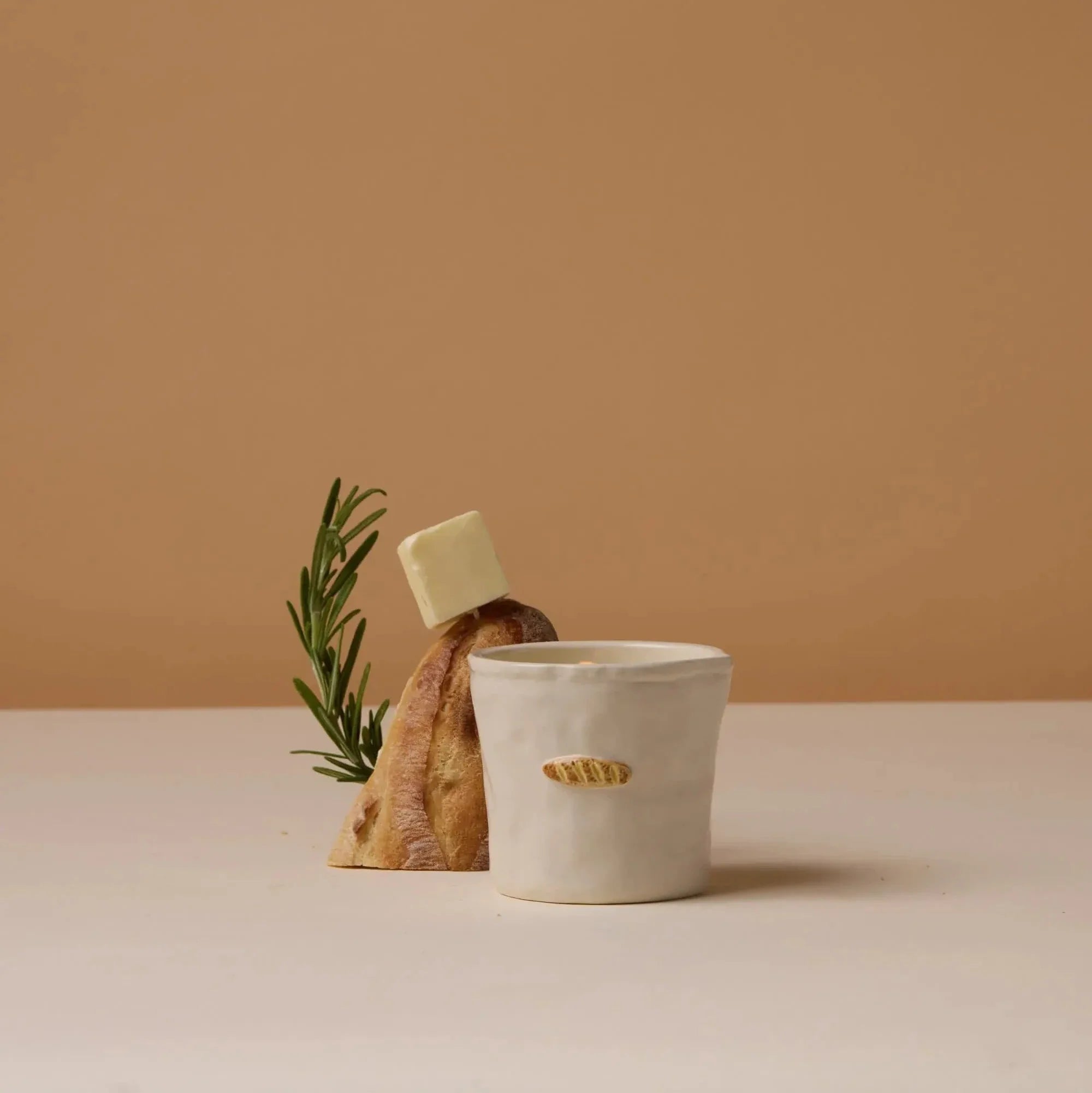 White ceramic cup with a plant and soap bar on a beige background