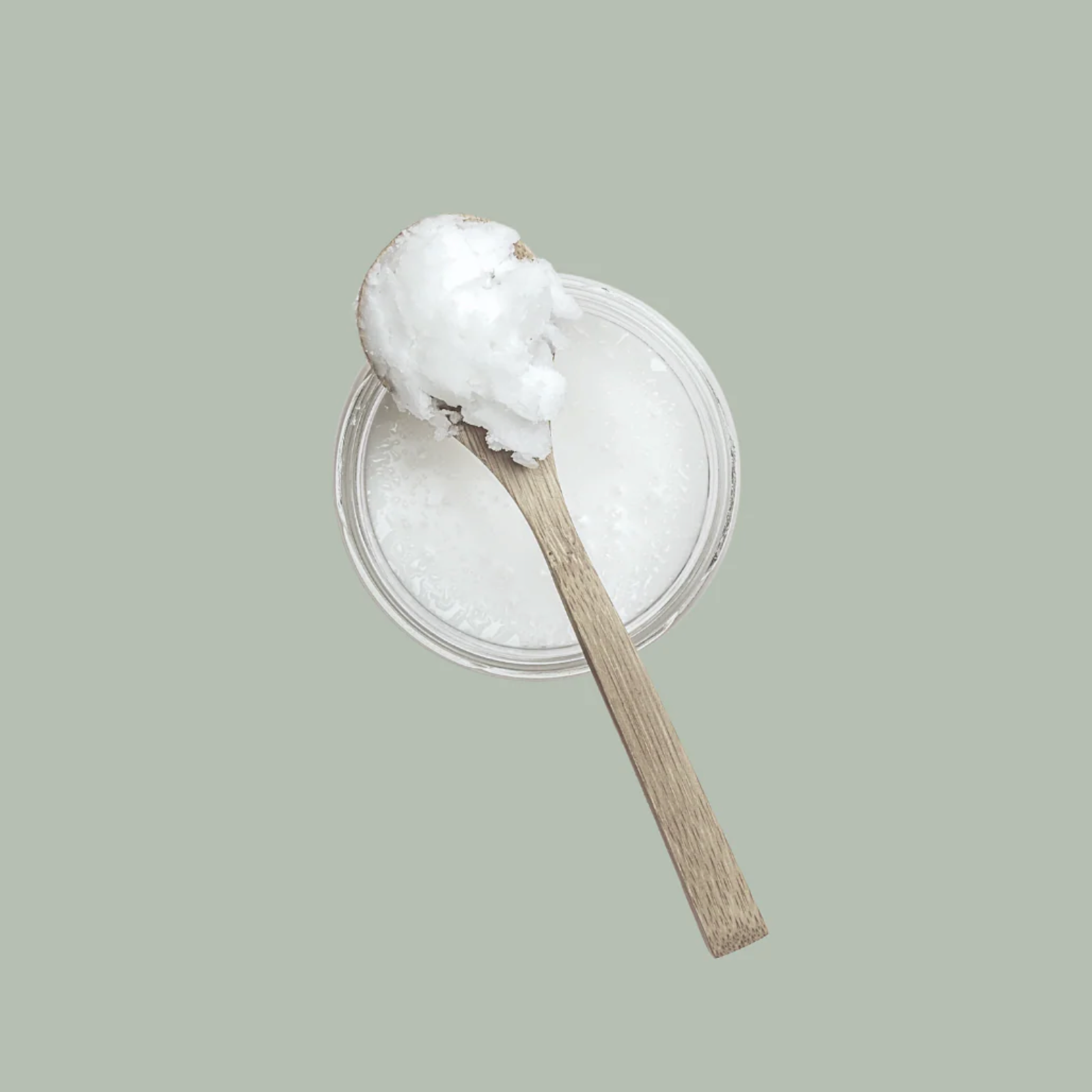 Wooden spoon with coconut oil on a light gray background