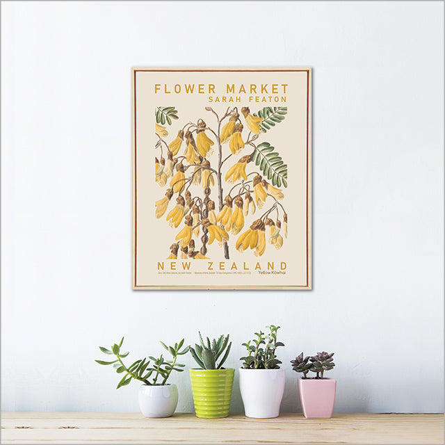 Framed Kowhai artwork of flowers with plants below on a white wall