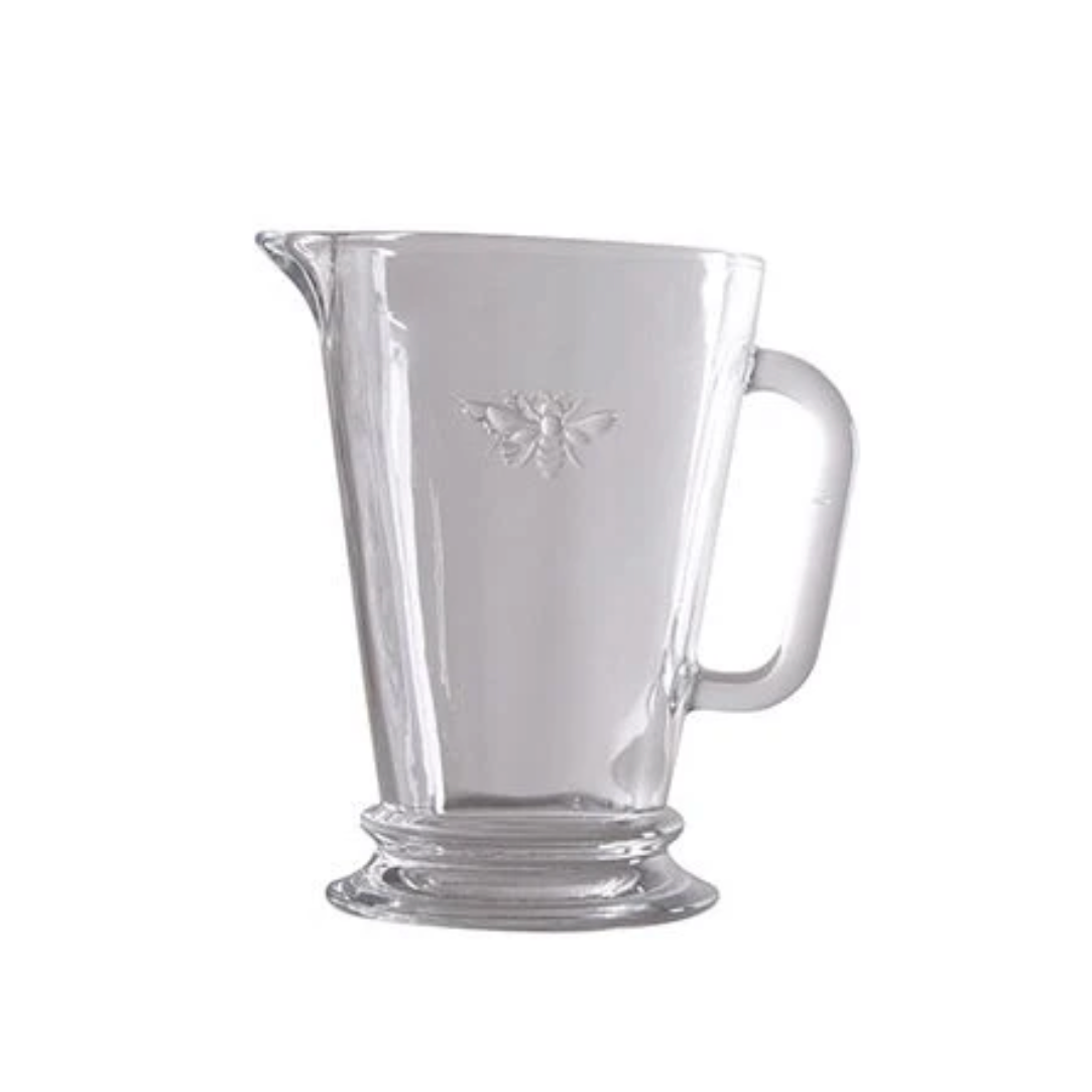 Clear glass pitcher with a handle on a white background