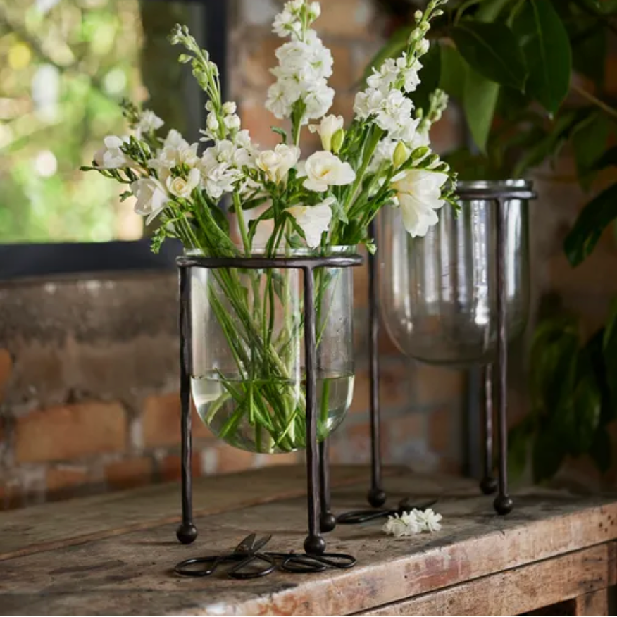 Two glass vases with white flowers on a wooden surface.