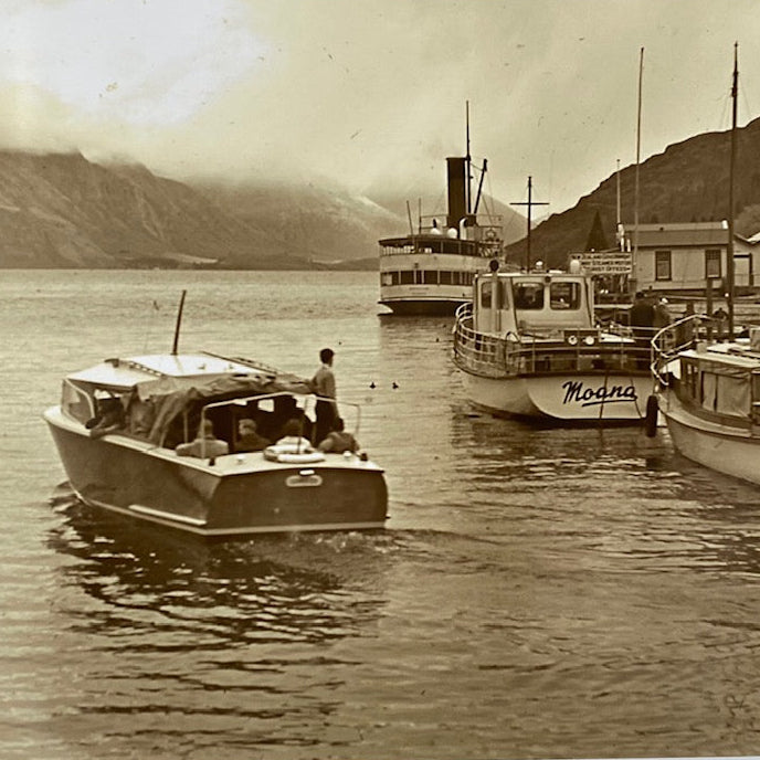 Vintage black and white photo of the Meteor boat on Lake Whakatipu with mountains in the background
