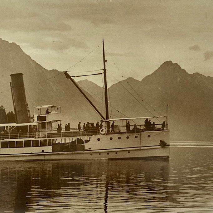 Vintage photograph of The Earnslaw on Lake Whakatipu with mountains in the background.