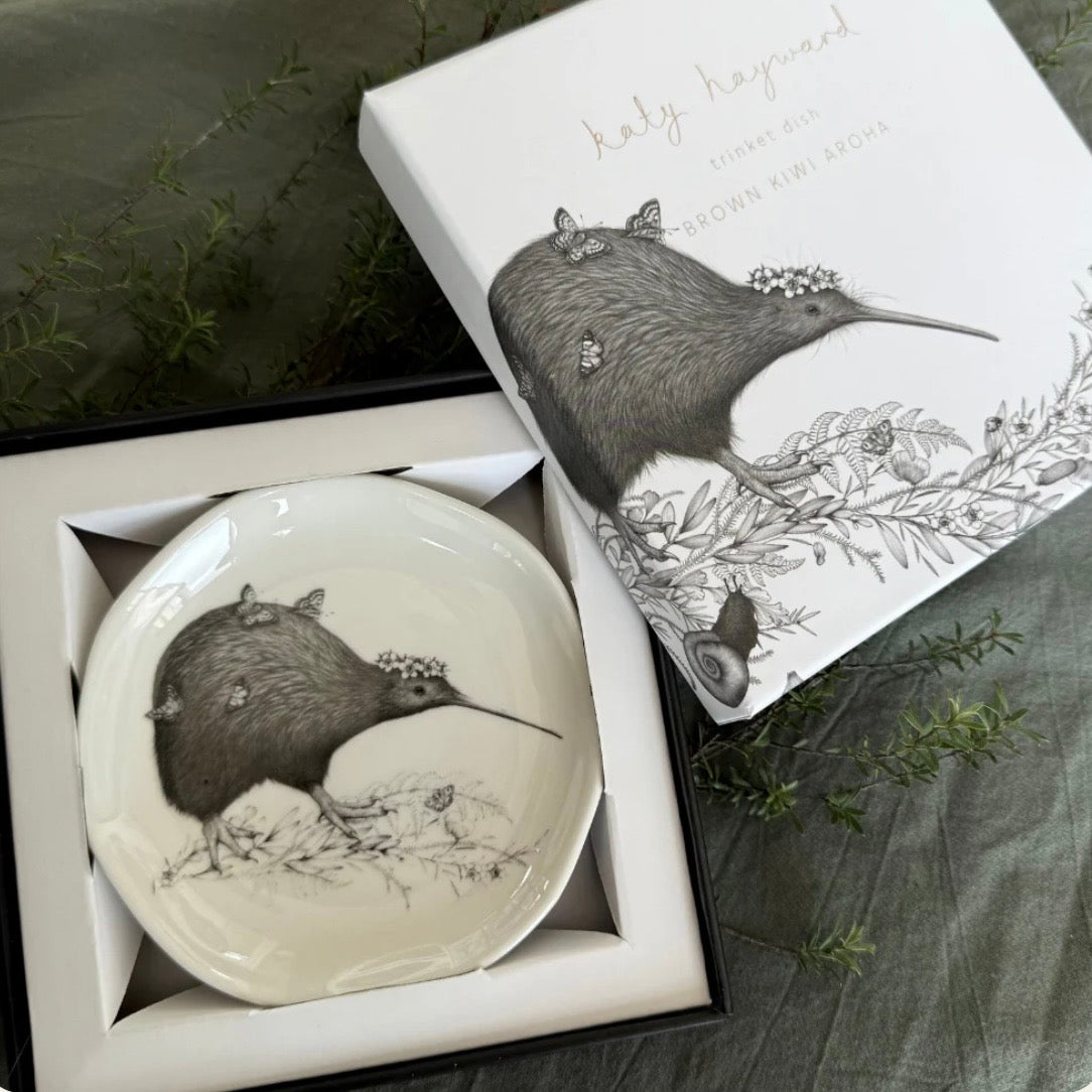 Decorative plate with a kiwi bird design in a box, with a matching cushion in the background.