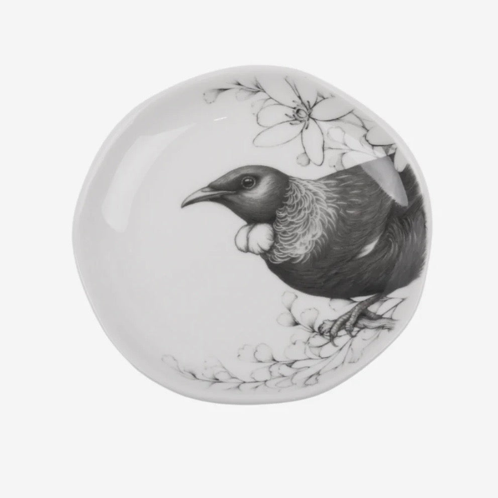 Round ceramic plate with a Tui bird design on a white background