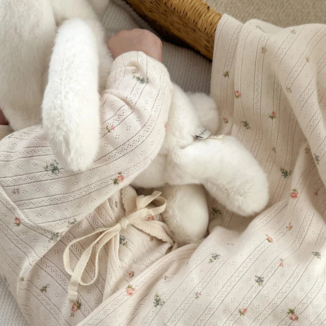 Close-up of a baby's outfit with a hat and white socks on a textured fabric background