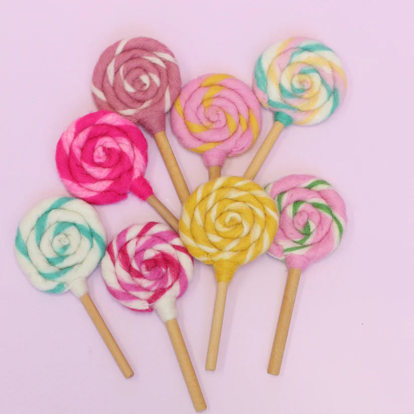Colorful lollipop swirls on sticks against a pink background