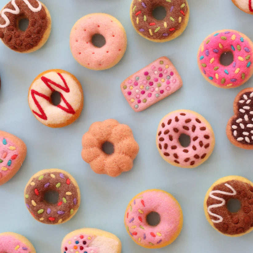 Pattern of colorful felt donuts with various glazes and sprinkles on a light blue background