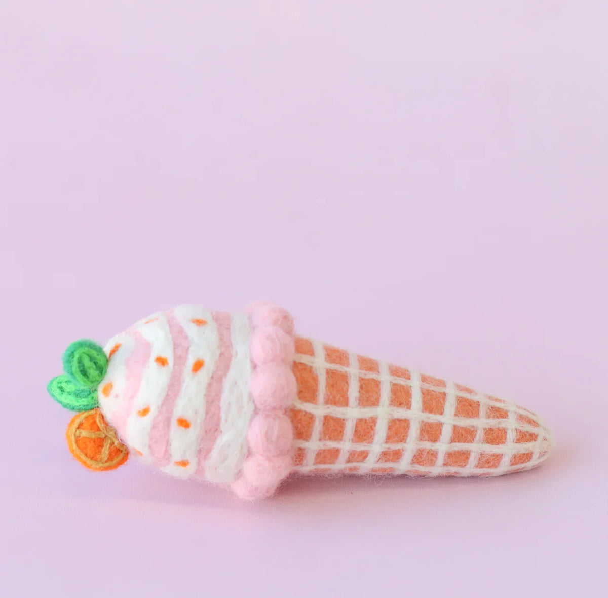 Felt ice cream cone toy with pink whipped cream and orange waffle pattern on a light purple background