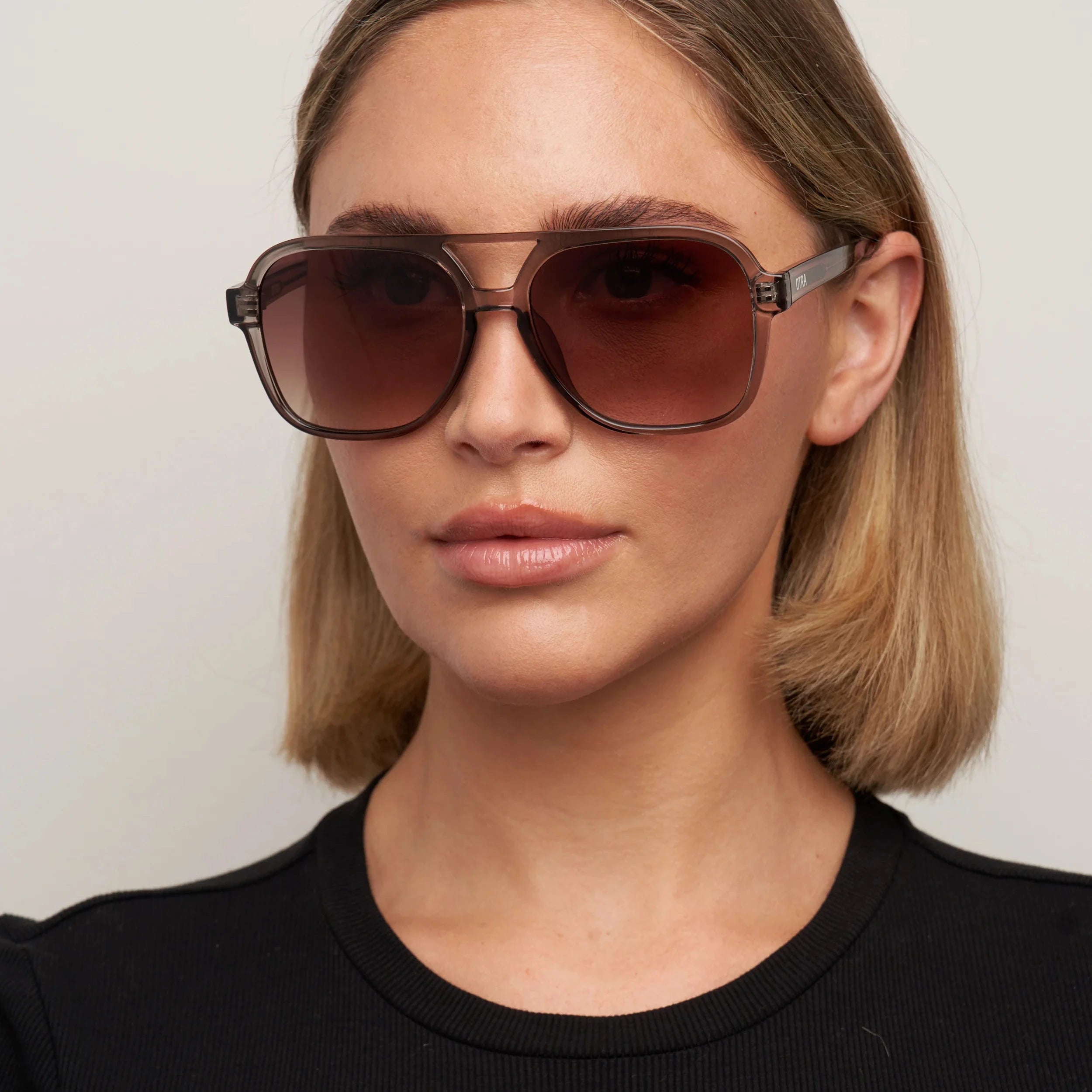 Woman wearing sunglasses with a neutral background