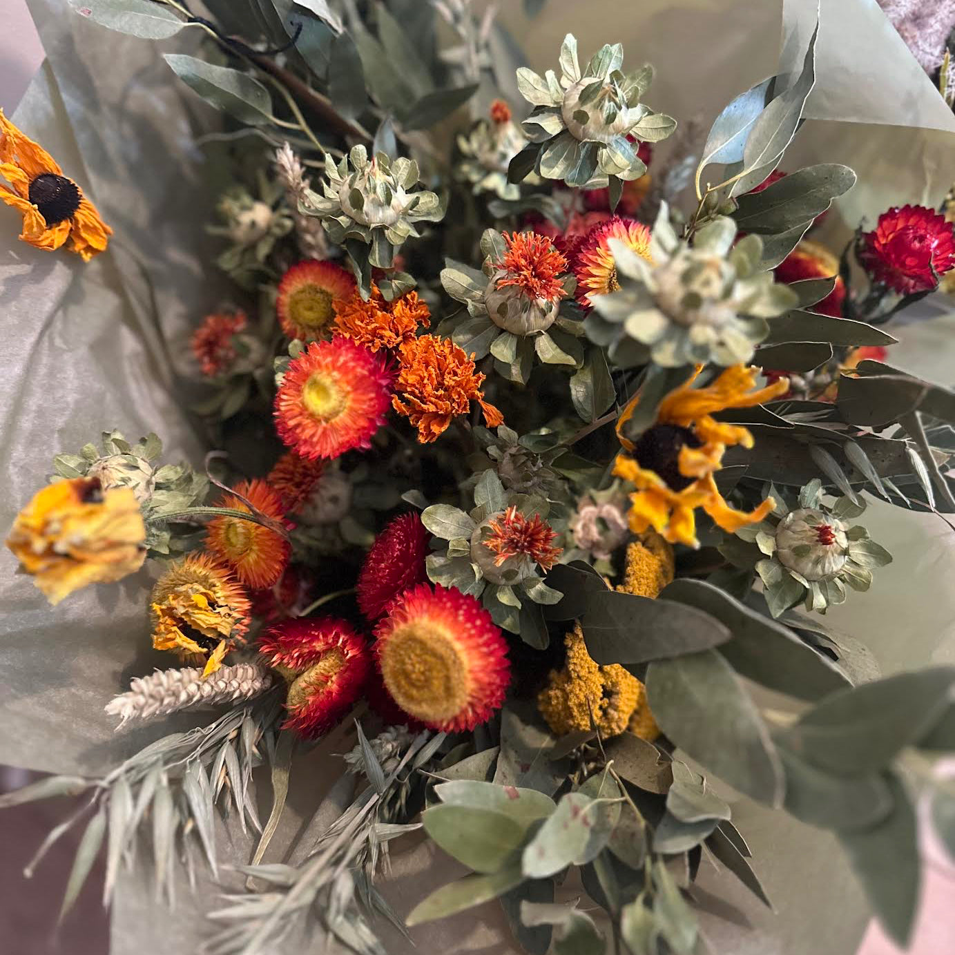 Bouquet of dried flowers with greenery on a light background