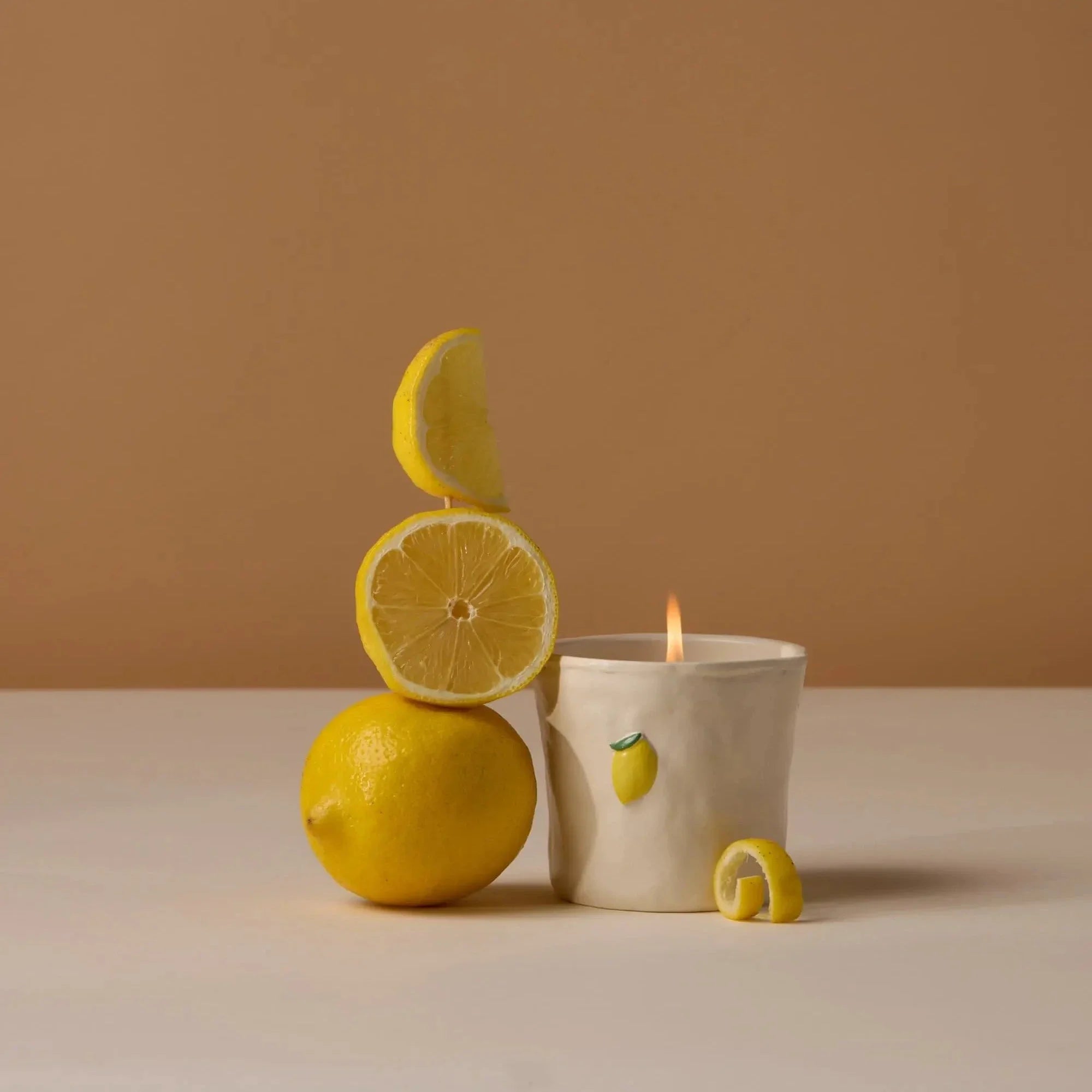 Candle with lemon design on a beige surface and background