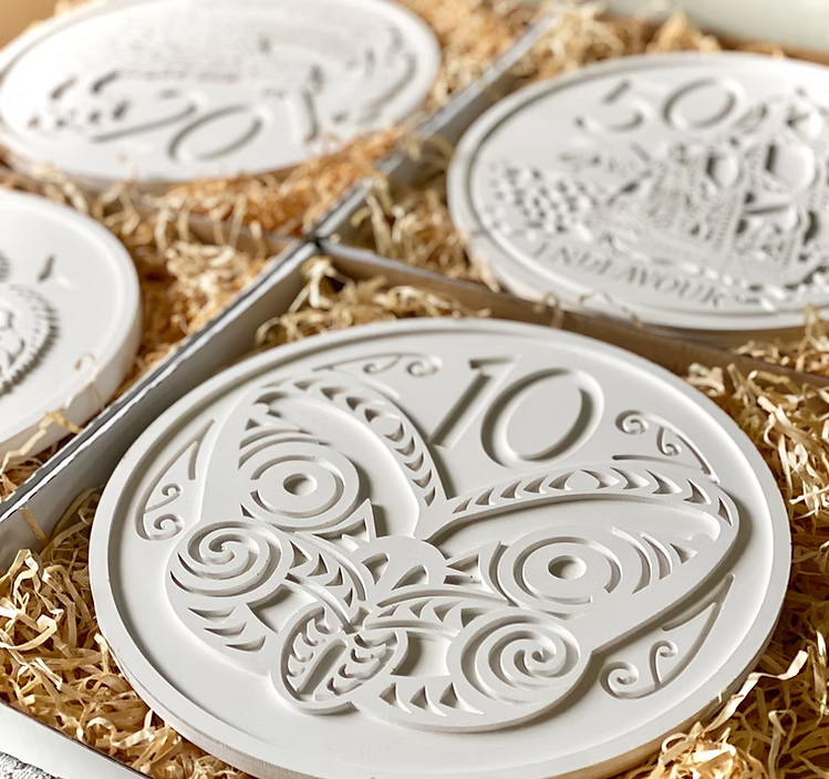 Decorative white ceramic tiles with intricate designs on a bed of straw.