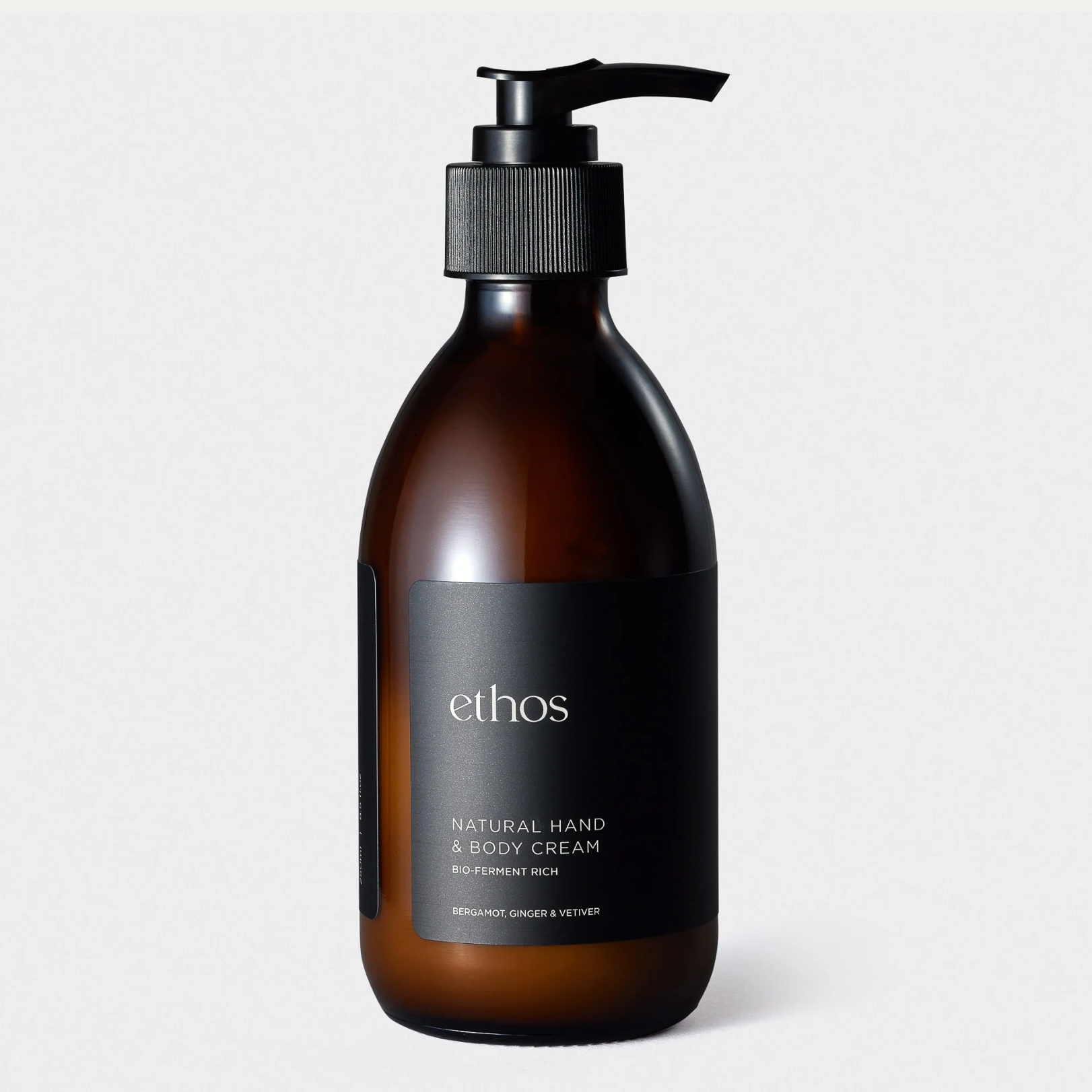 Brown bottle of ethos natural hand & body cream on a light gray background