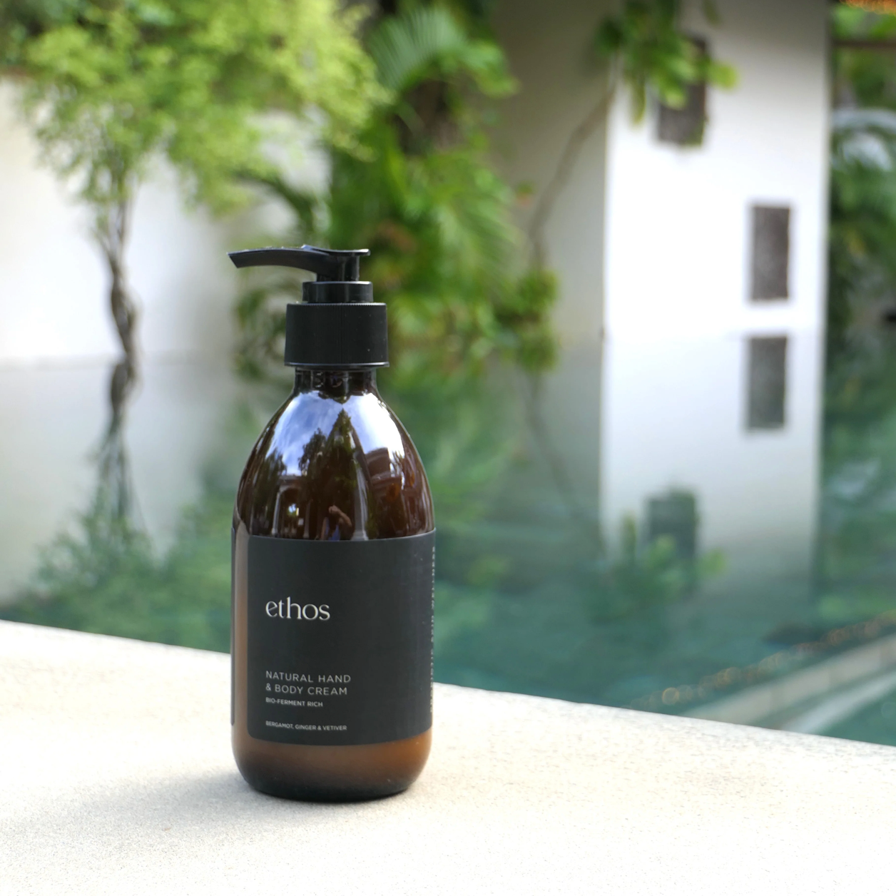 Ethos hand and body cream bottle on a surface with a blurred outdoor background