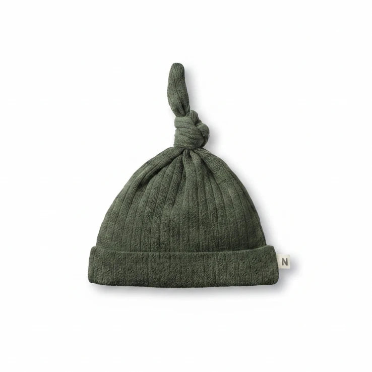 Green knotted baby hat on a white background