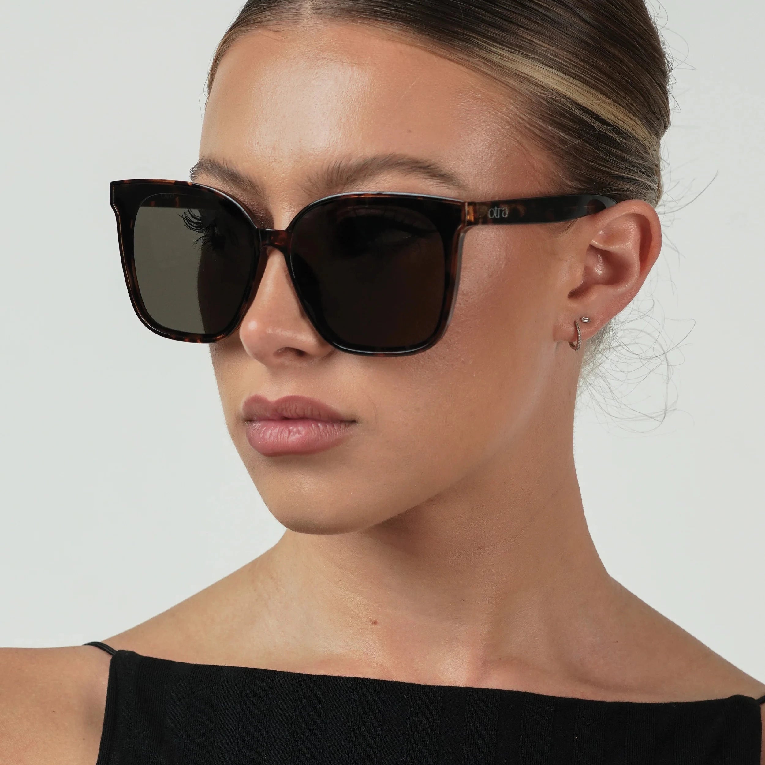 Woman wearing black sunglasses with a plain background