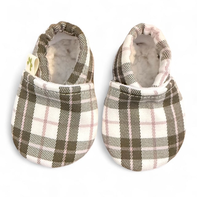 A pair of Pretty Kiwi handmade in New Zealand soft baby booties with a olive, natural and pink plaid patterned fabric exterior and a plush cream lining, shown on a white background.
