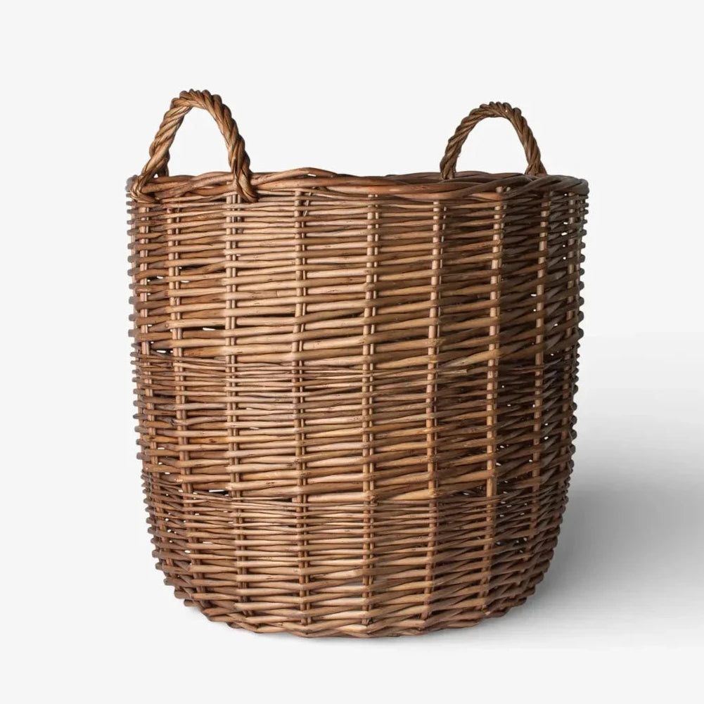 A natural brown woven wicker basket with two loop handles, photographed on a clean white background with a soft shadow.
