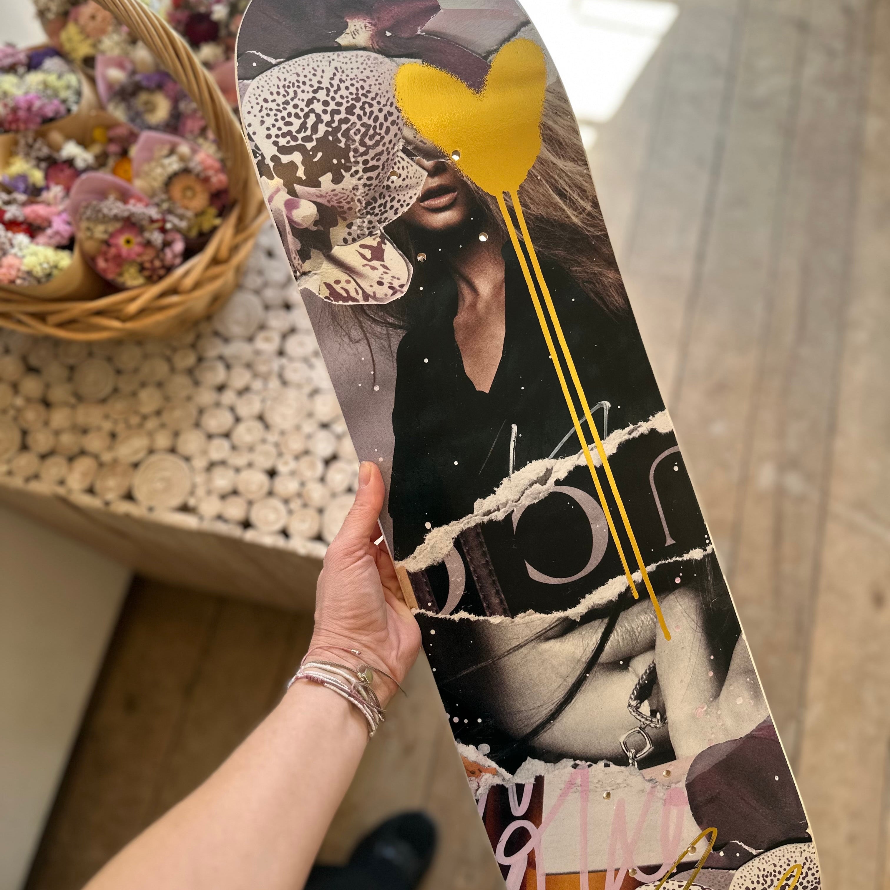 Person holding a skateboard with artistic design in a casual indoor setting