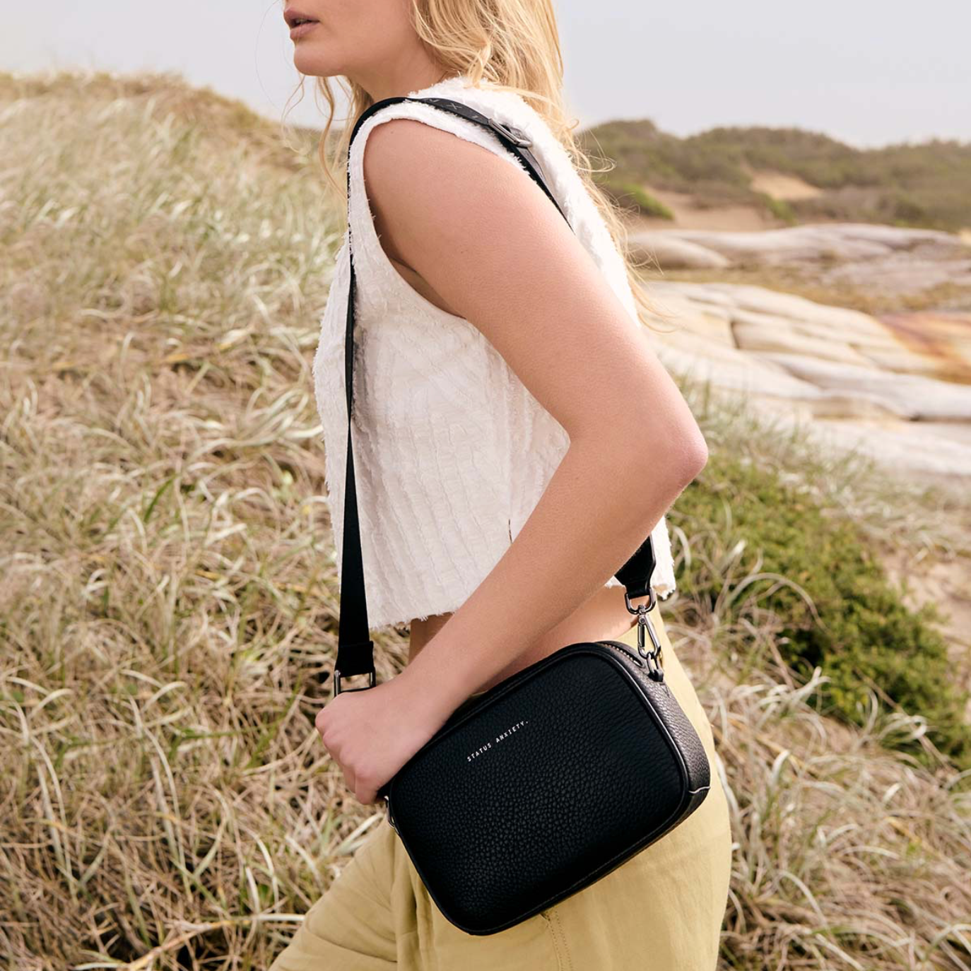 Woman holding a black handbag in a natural setting