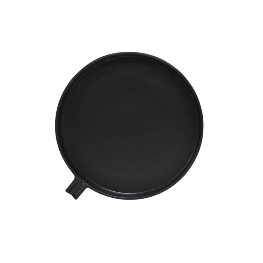 A round black cast iron skillet or griddle plate with a small side handle, shown from a top-down view on a plain white background.