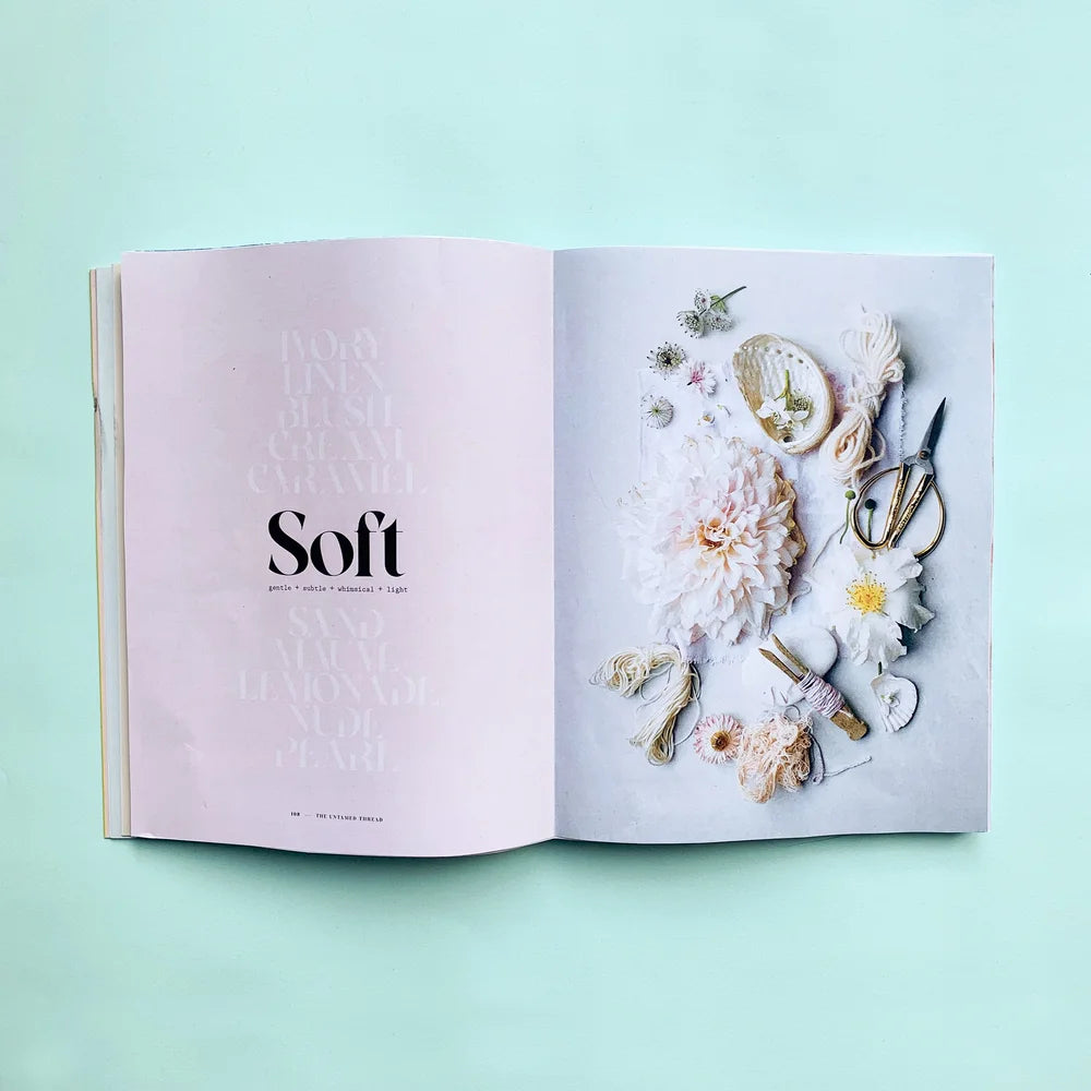 An open book spread on a mint green background. The left page is pale pink with the word 'Soft' in large black font and faintly repeated words above it.