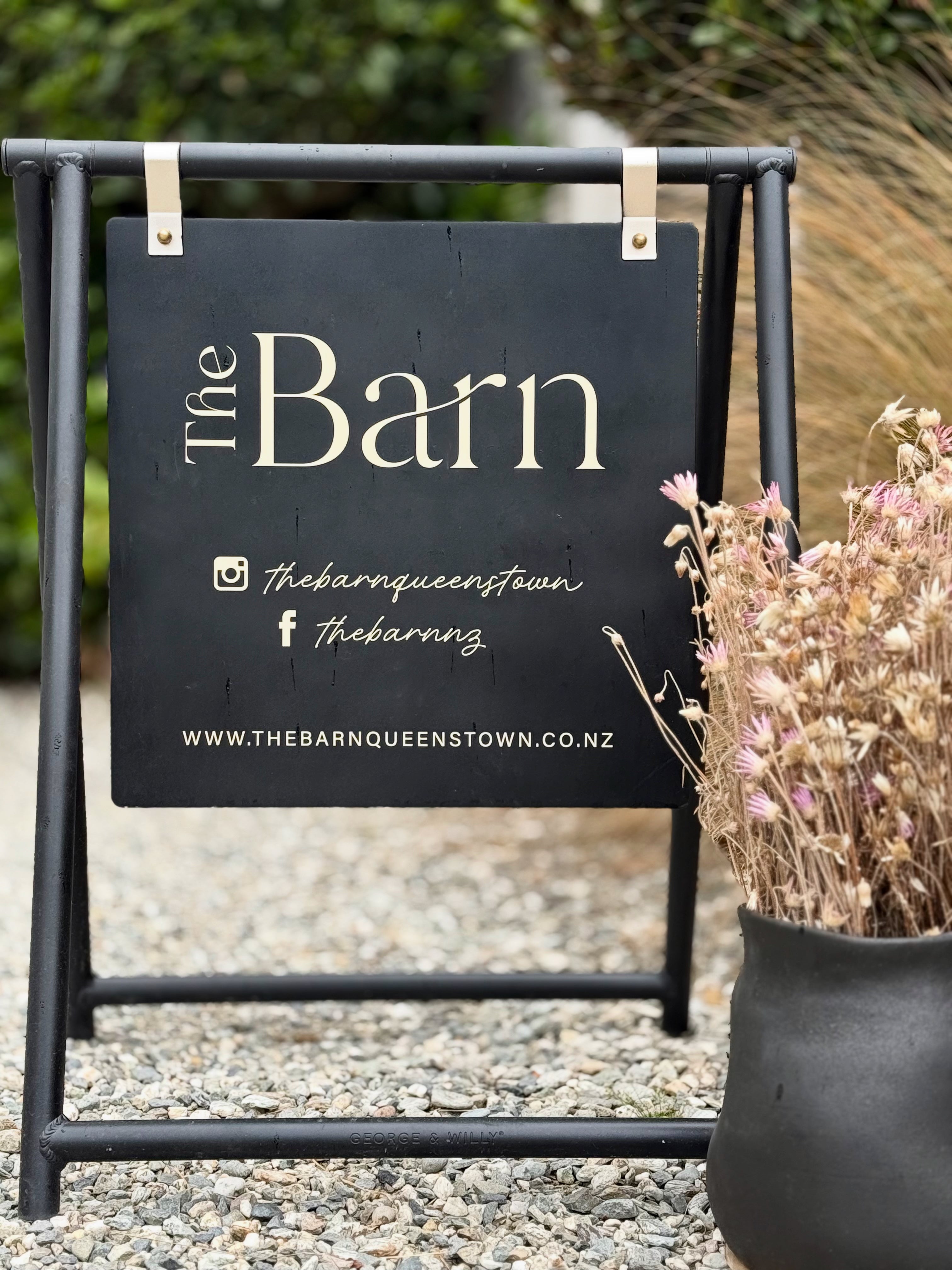 Outdoor sign for 'The Barn' with branding elements on a stand.