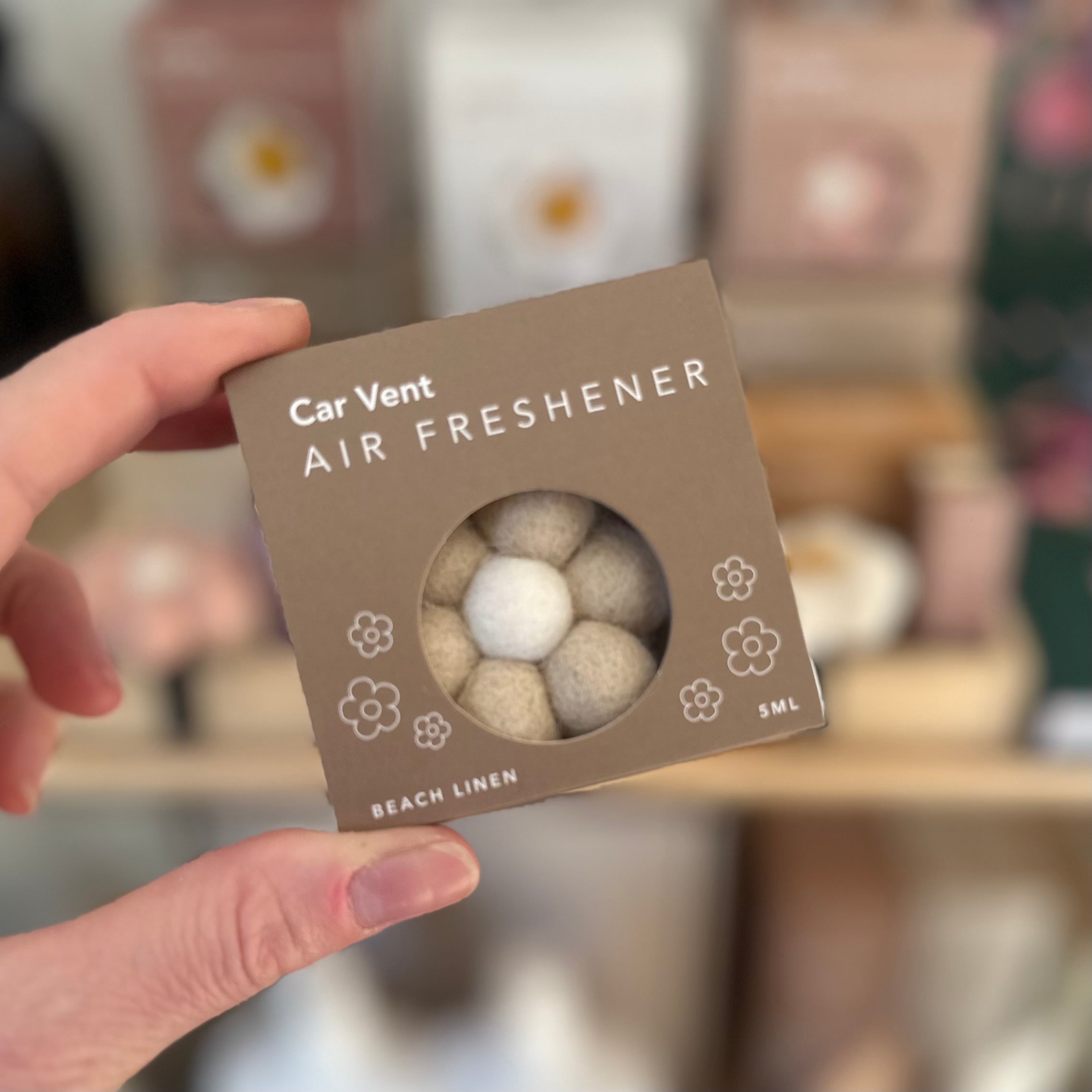 Car Vent Air Freshener packaging held by a hand with a blurred background