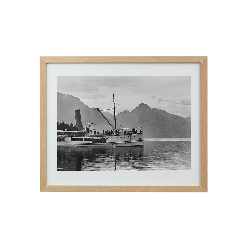 Framed black and white photograph of The Earnslaw on water with mountains in the background
