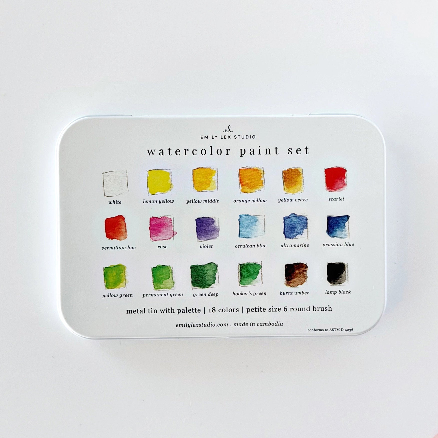 A metal tin watercolor paint set by Emily Lee Studio, featuring 18 color paint swatches printed on the lid, set against a clean white background.
