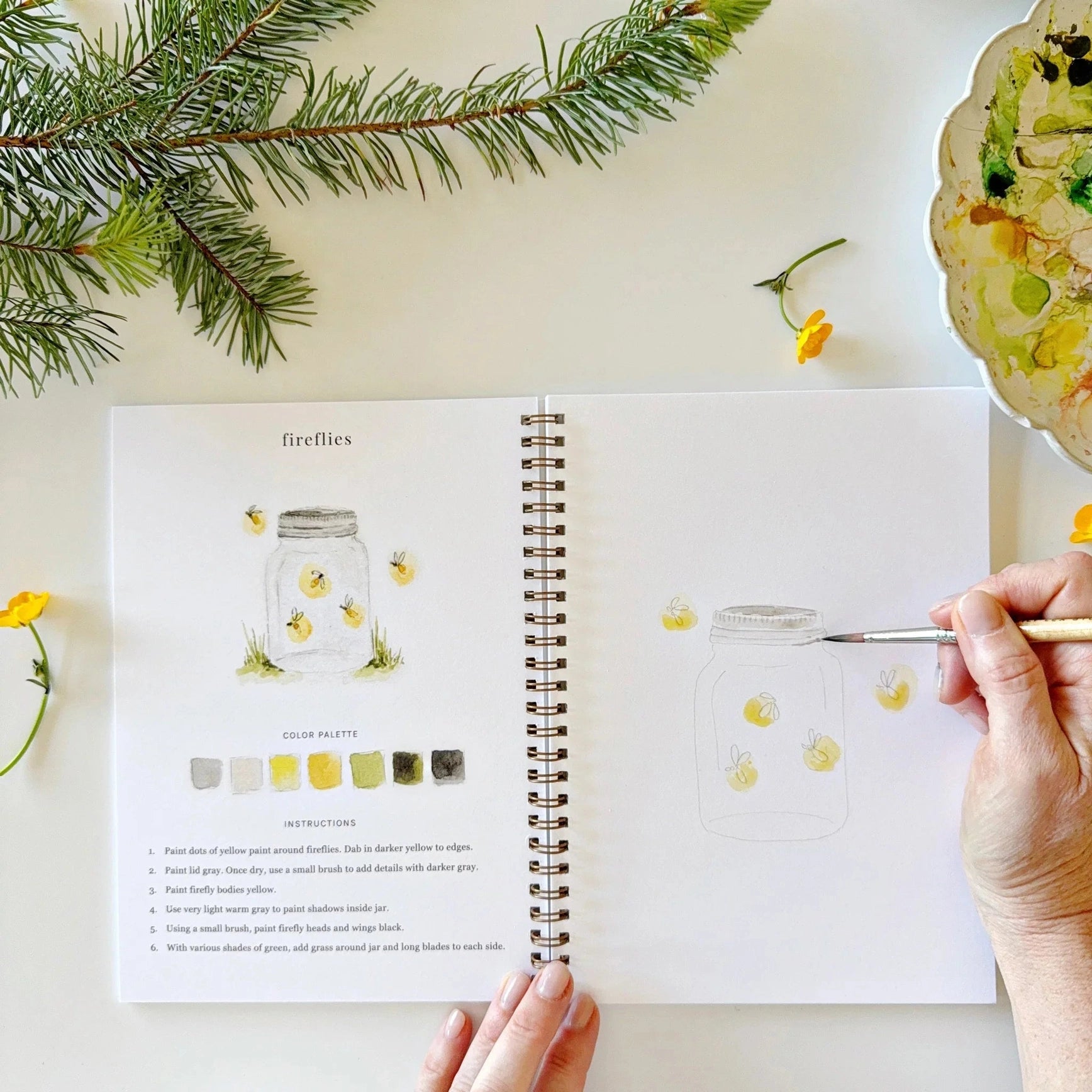 Person drawing a firefly illustration in a sketchbook with nature elements around