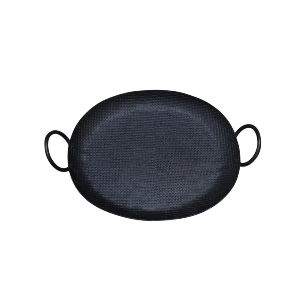 A black oval cast iron kadhai with two loop handles, shown from a top-down view on a plain white background.