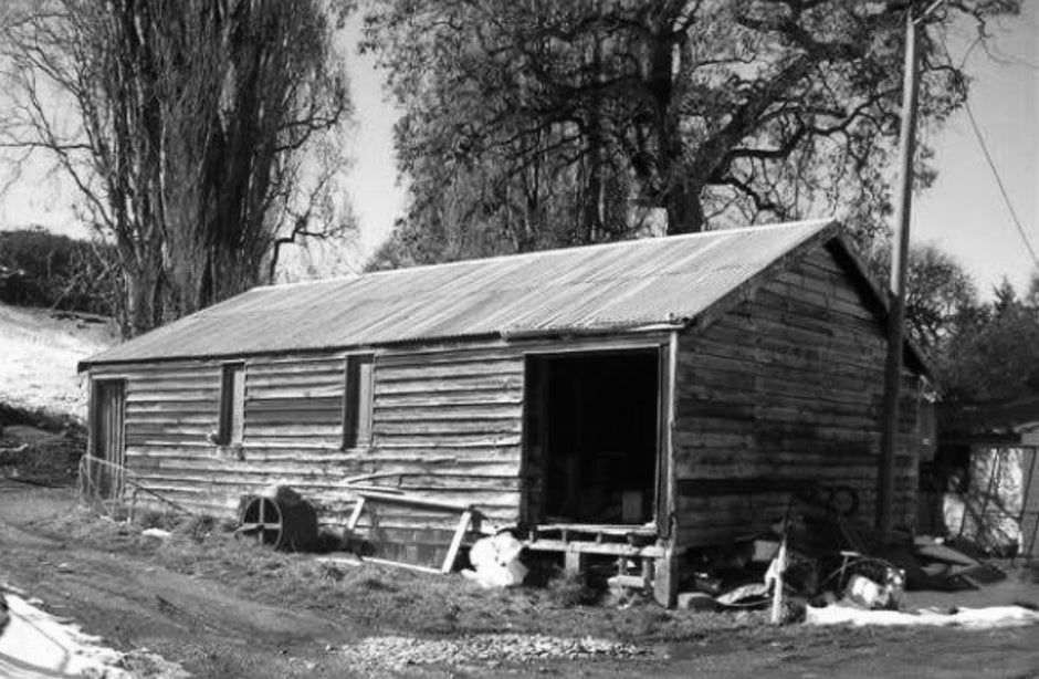 Old wooden cabin with a metal roof in a rural setting
