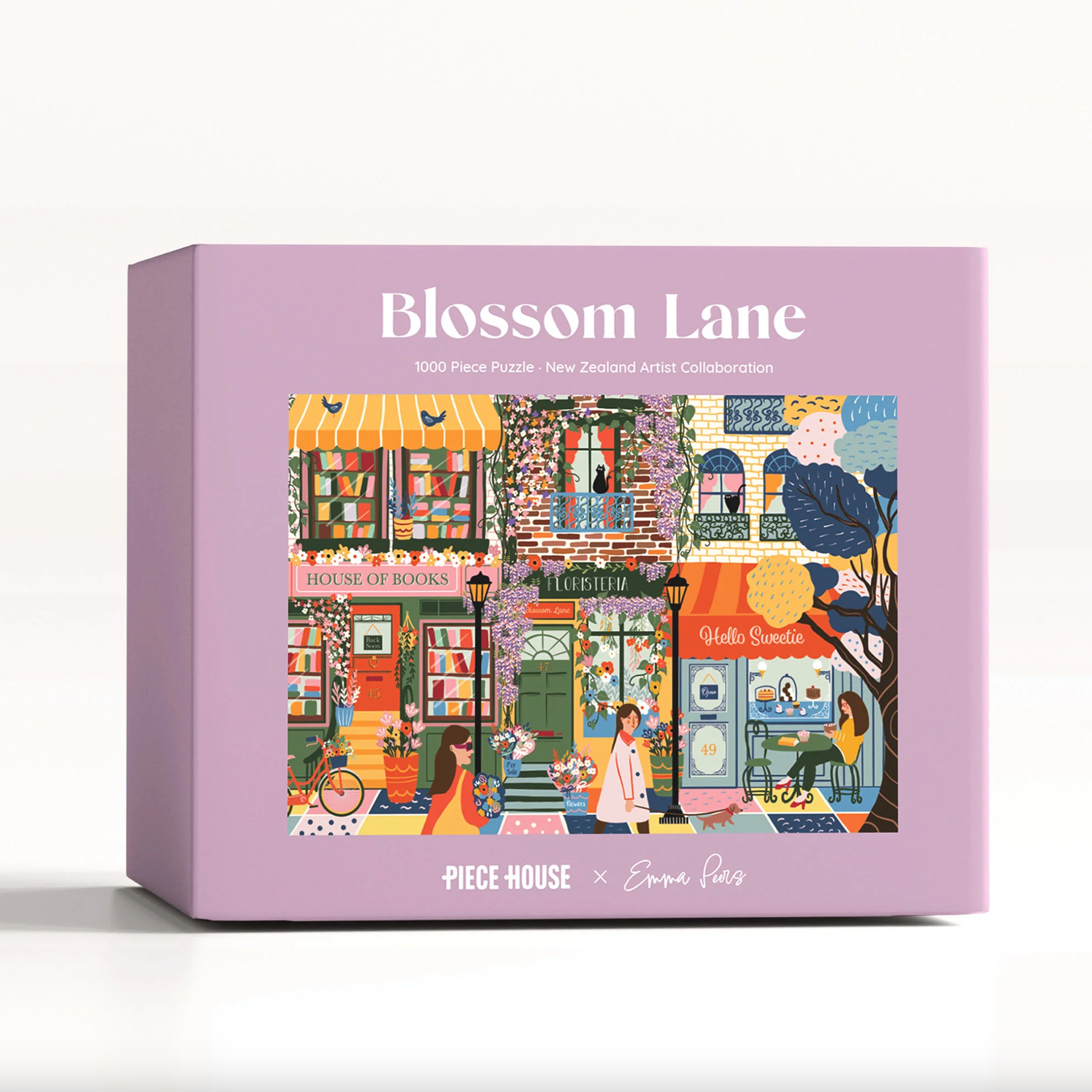 A lavender puzzle box labeled 'Blossom Lane' with a colorful illustrated storefront scene on the front, photographed on a clean white background.