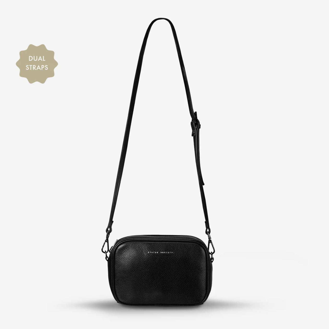 Black crossbody bag with dual straps on a light gray background