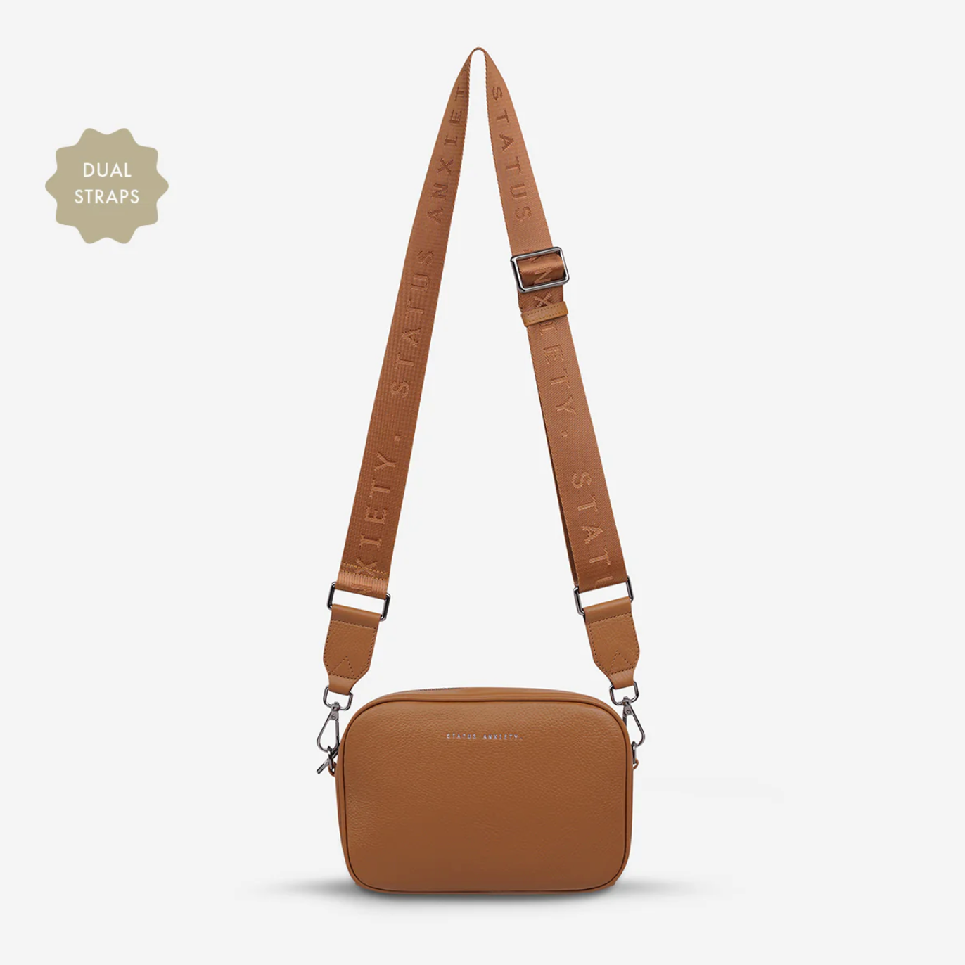 Brown crossbody bag with dual straps on a light beige background