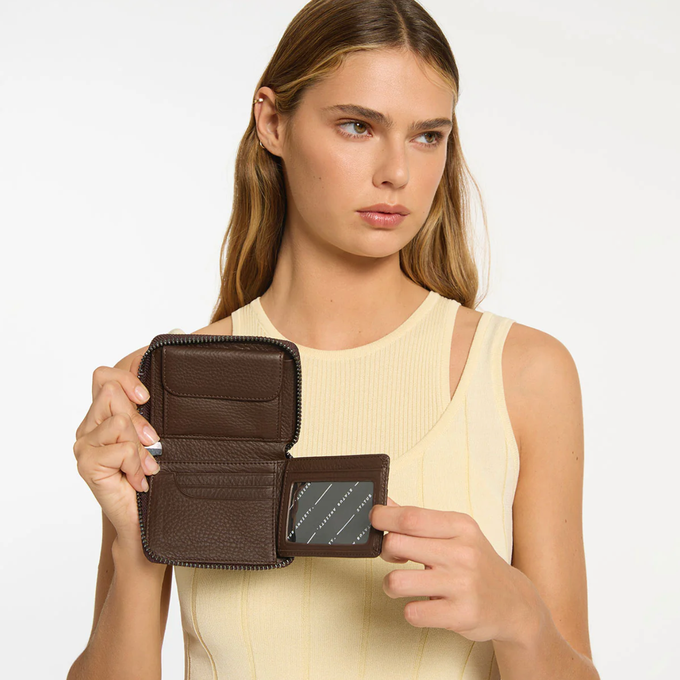 Woman holding a brown wallet against a plain background