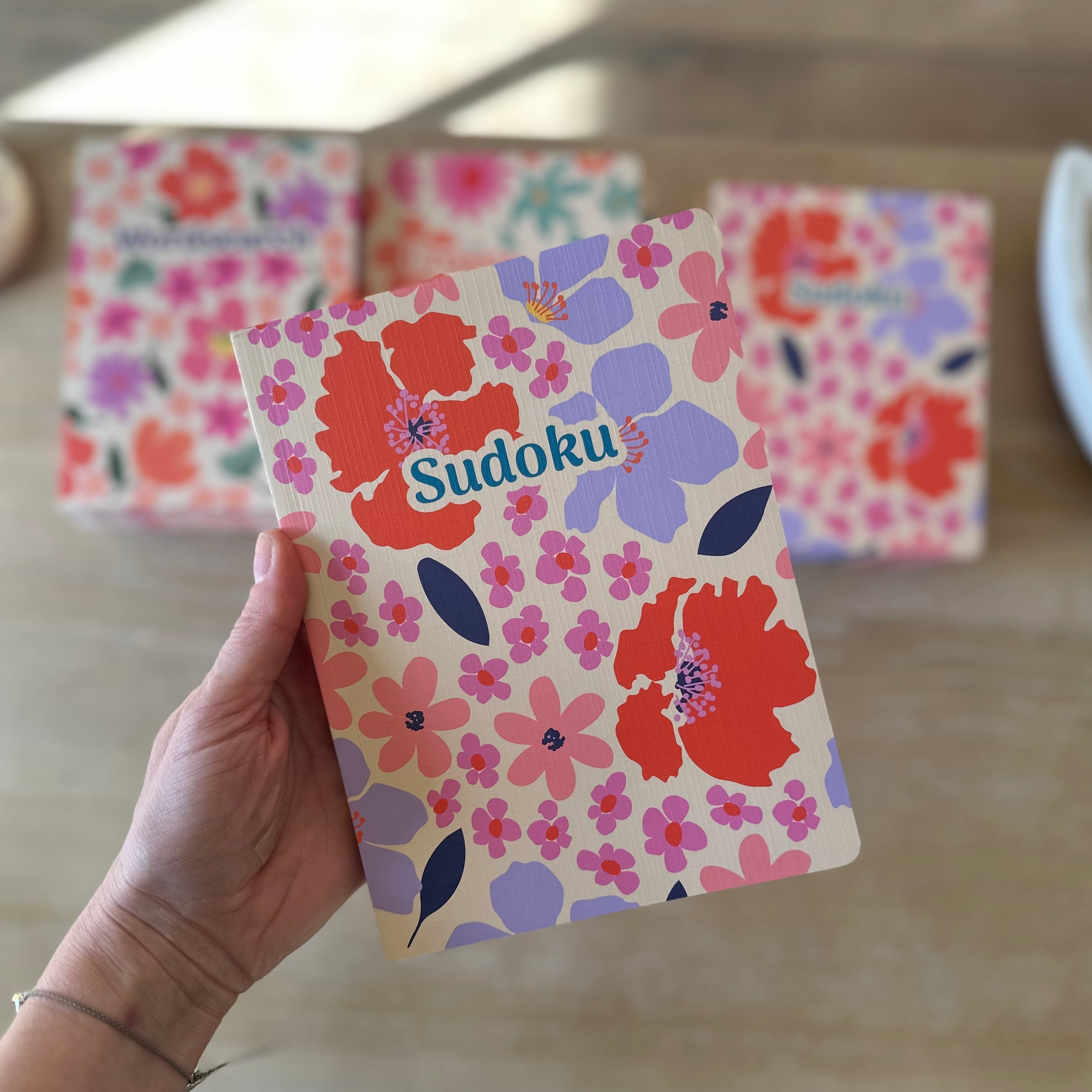 Floral Sudoku game card held by a hand with more cards in the background.
