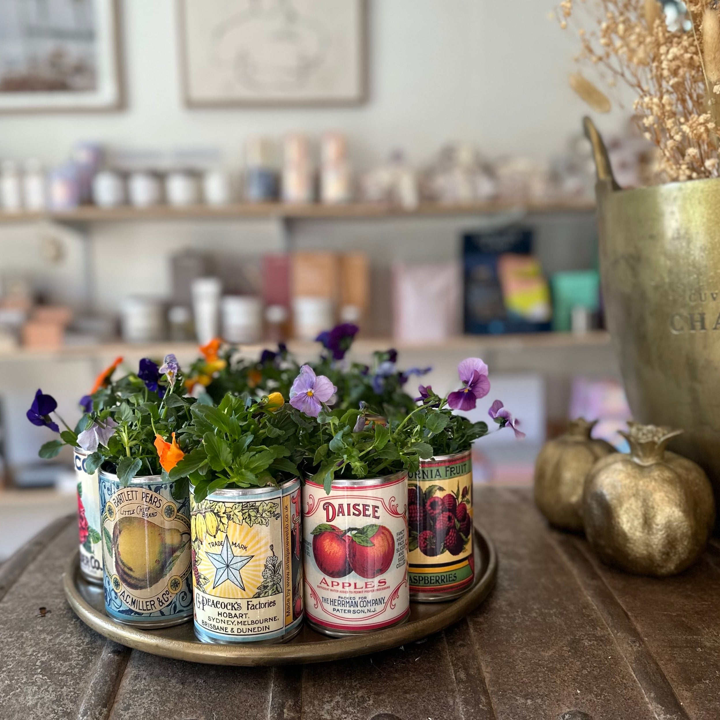 Decorative setup with vintage-style tins and flowers on a rustic table in a cozy interior setting.