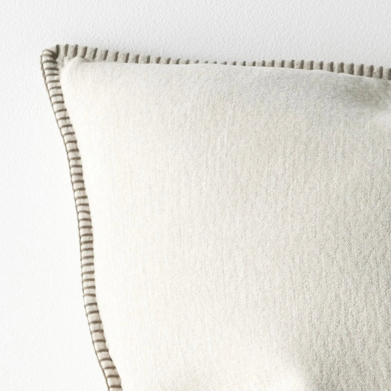 Close-up of a textured pillow with a striped edge on a light background