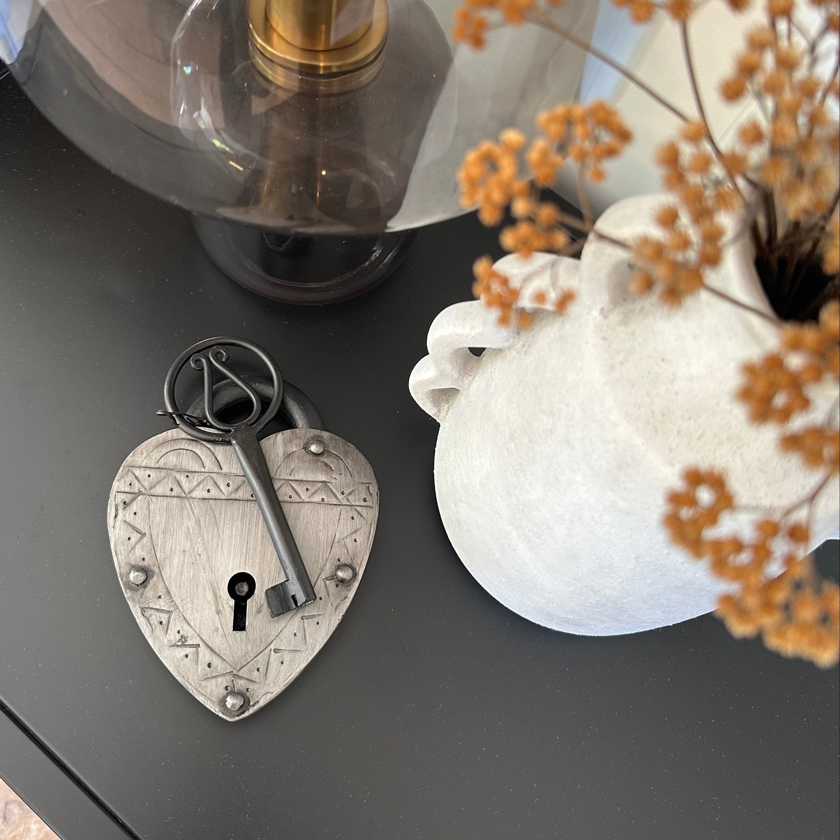 Decorative keyhole with a bottle and flowers on a dark surface