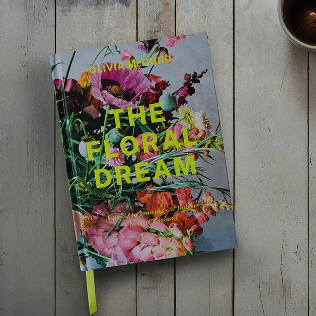 Floral Book titled 'The Floral Dream' on a wooden surface with a cup of tea and flowers.