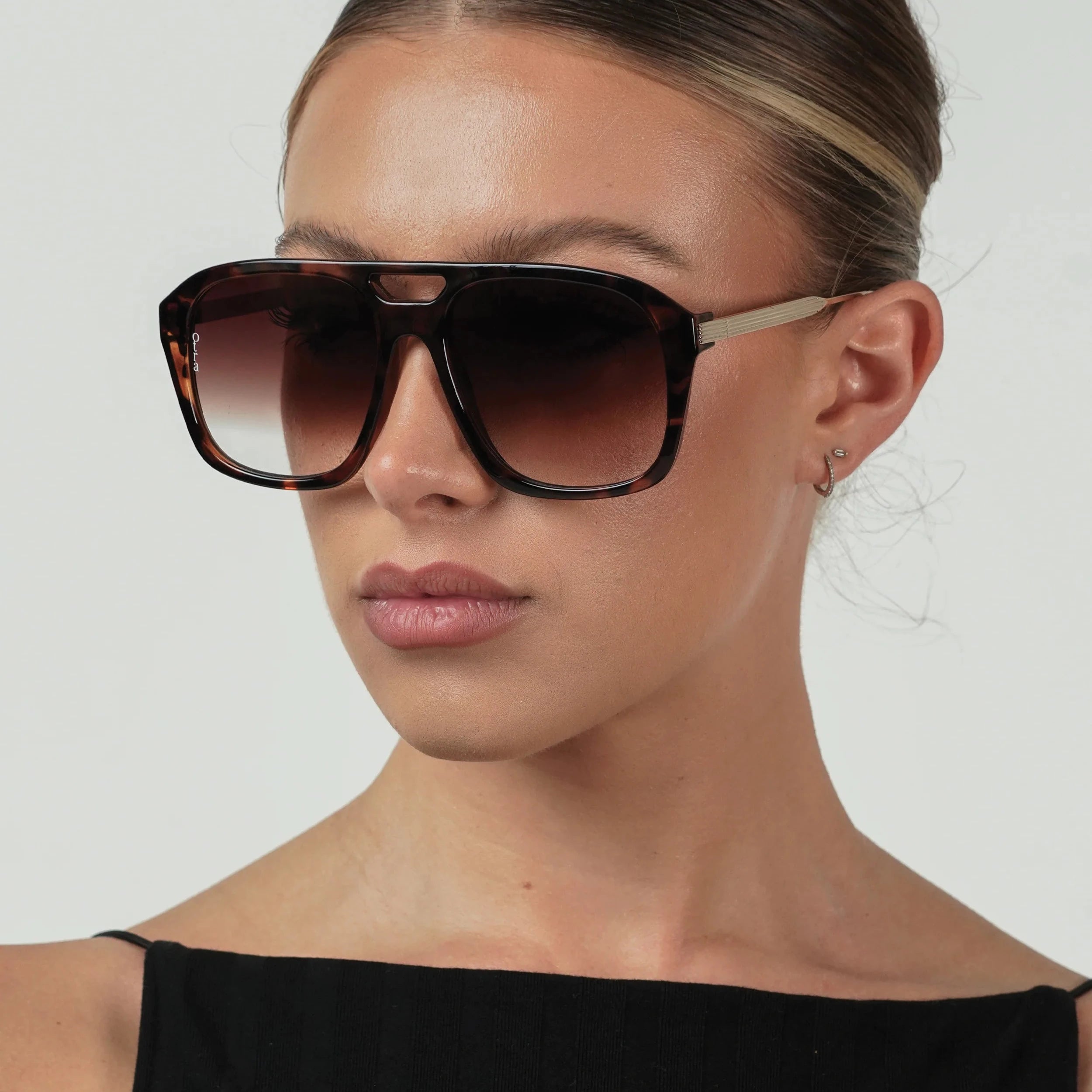 Woman wearing a pair of sunglasses with a plain background