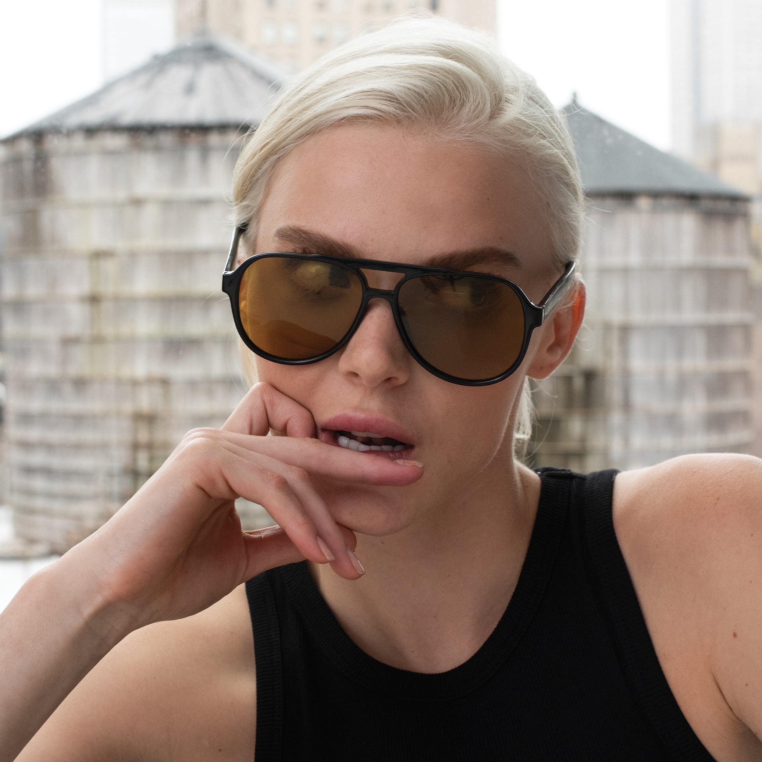 Person wearing sunglasses with a blurred cityscape background