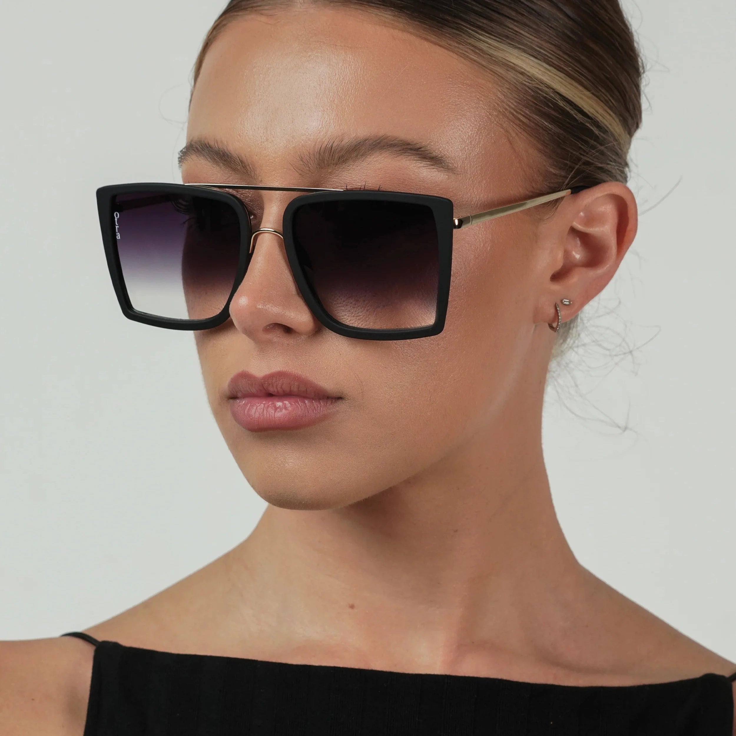 Woman wearing black sunglasses with a plain background