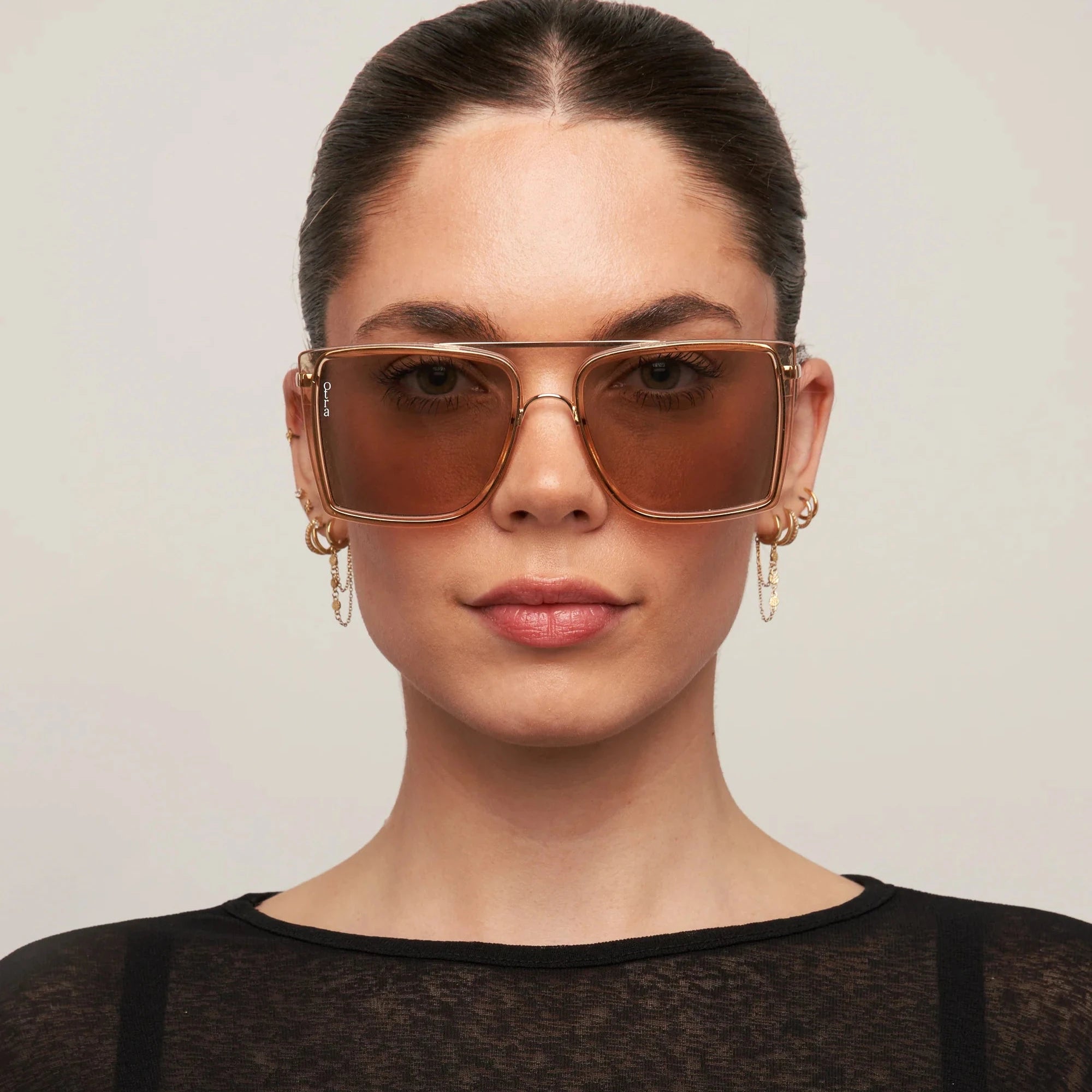 Woman wearing brown sunglasses with a plain background